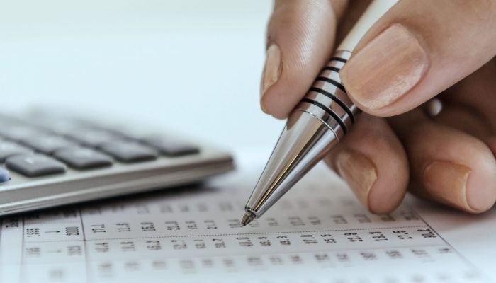 Woman auditing data printout with calculator